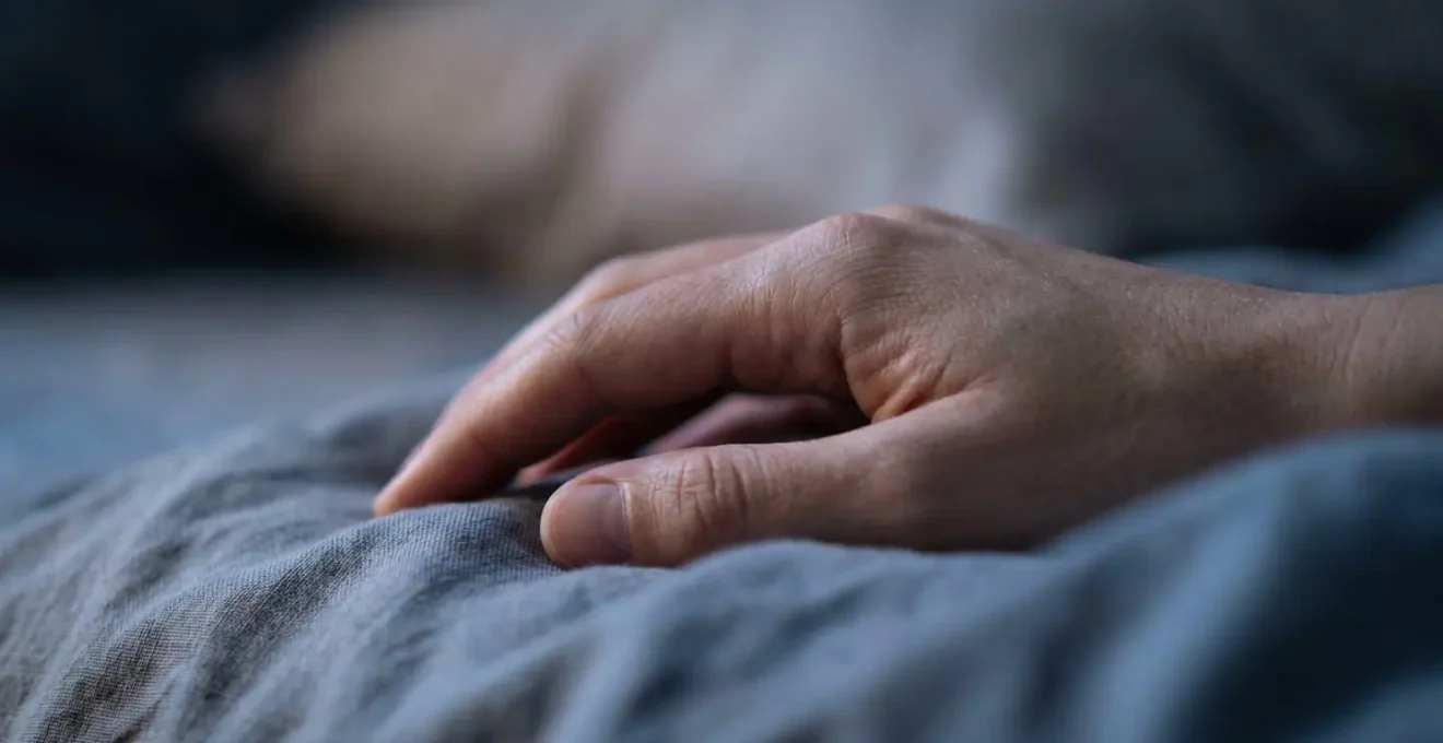 Vue macro d'une main détendue sur un drap illustrant la détente profonde