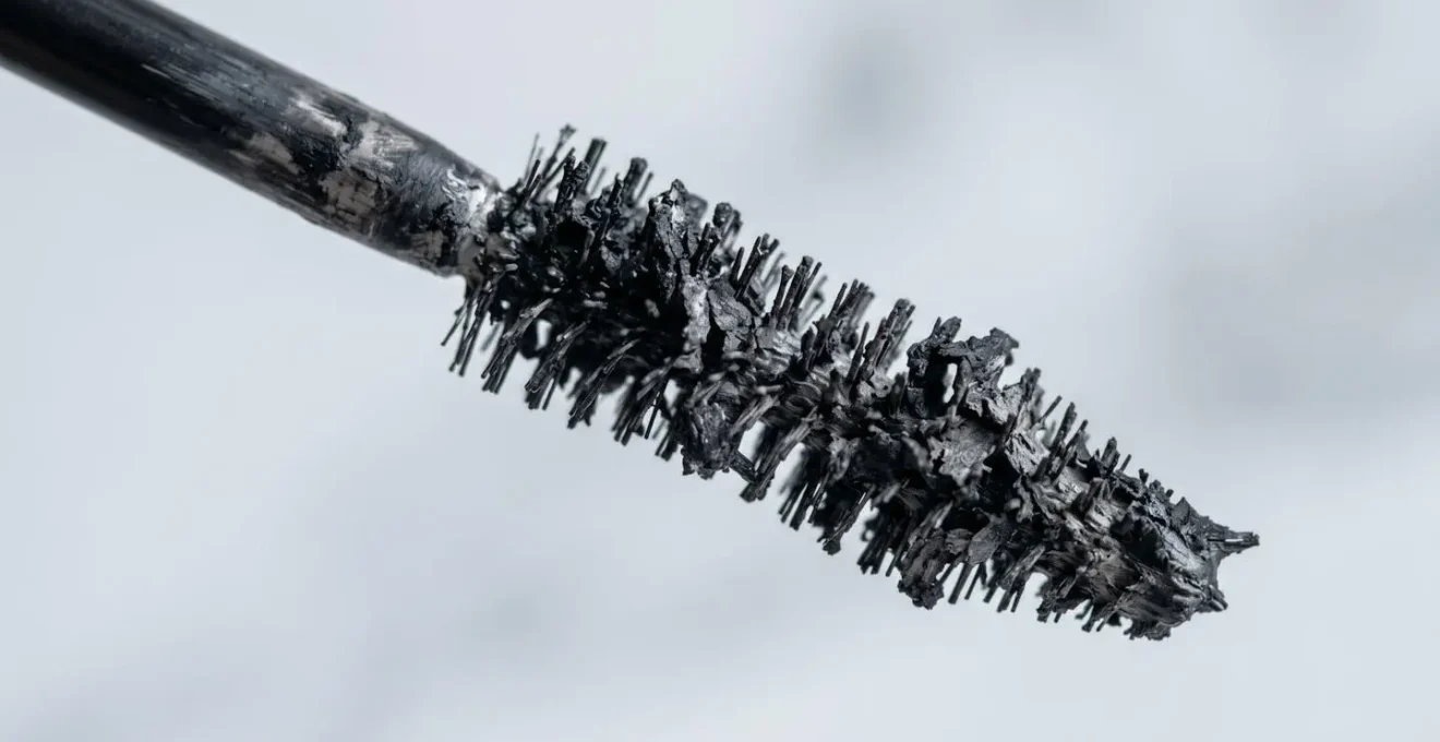 Gros plan sur une brosse de mascara montrant une texture dégradée et des grumeaux
